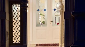 A grand staircase with ornate railings and a patterned carpet leading to a white door with glass panels. - Wohnung in Historischem Herrenhaus (Rhodt unter Rietburg)