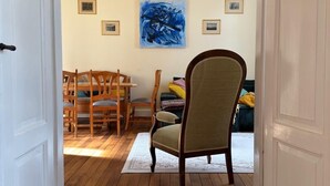 A wooden-floored hallway leading to a dining area with a chandelier, wooden chairs, and a large abstract painting on the wall. - Wohnung in Historischem Herrenhaus (Rhodt unter Rietburg)