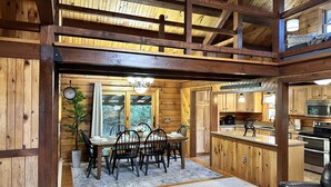 L’intérieur d’un chalet en bois comprend un coin repas, une cuisine et un balcon.