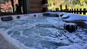 Un bain à remous avec un revêtement extérieur en bois et une décoration en forme d’étoile, entouré d’arbres et d’une clôture en bois.