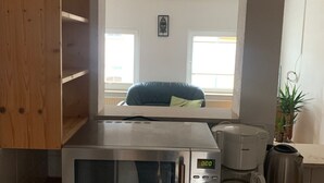A compact kitchen with a built-in microwave, coffee maker, and kettle.