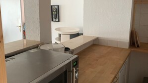 A kitchen with a stainless steel microwave, wooden cabinets, and a white countertop.