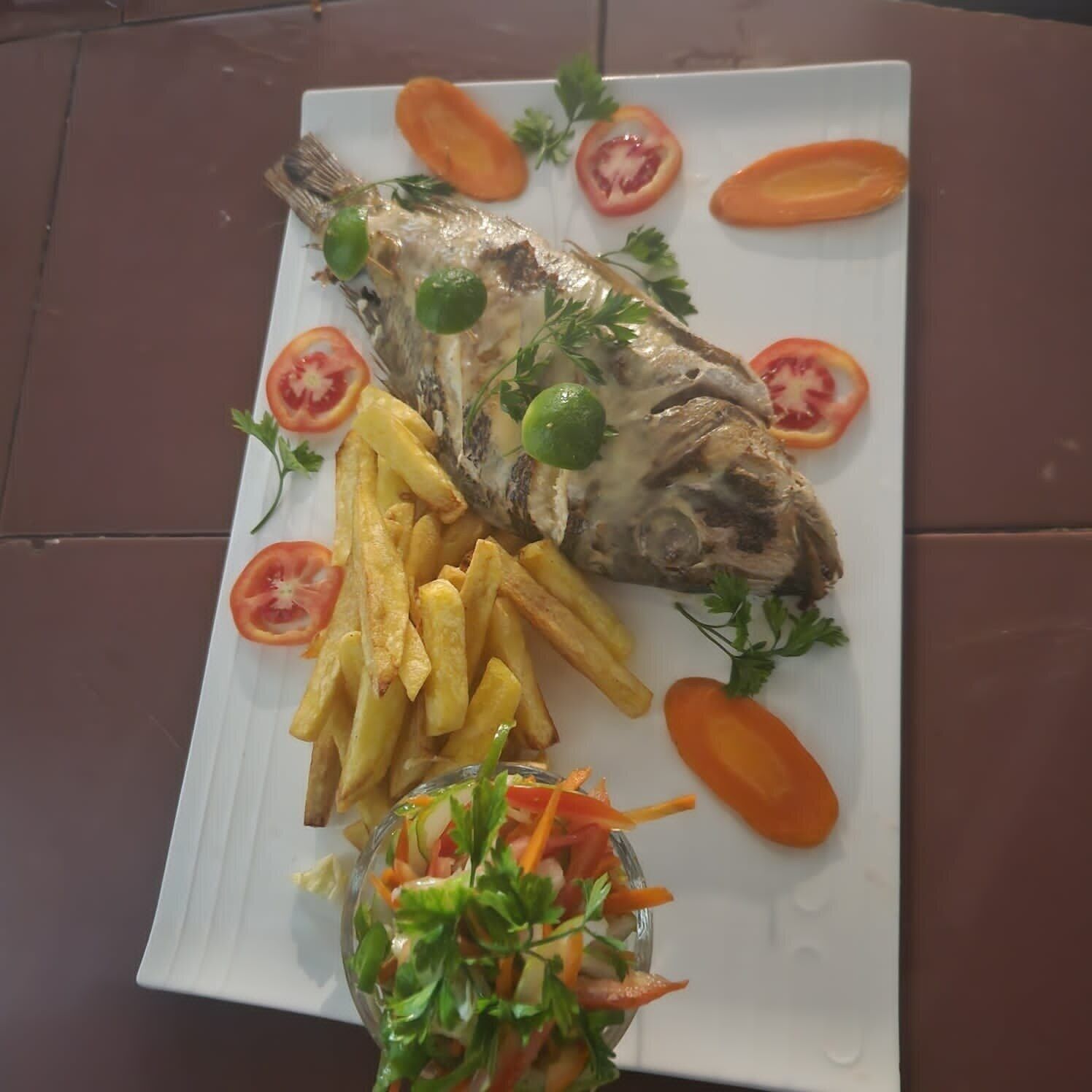 A plate with a whole fish, French fries, and a salad.
