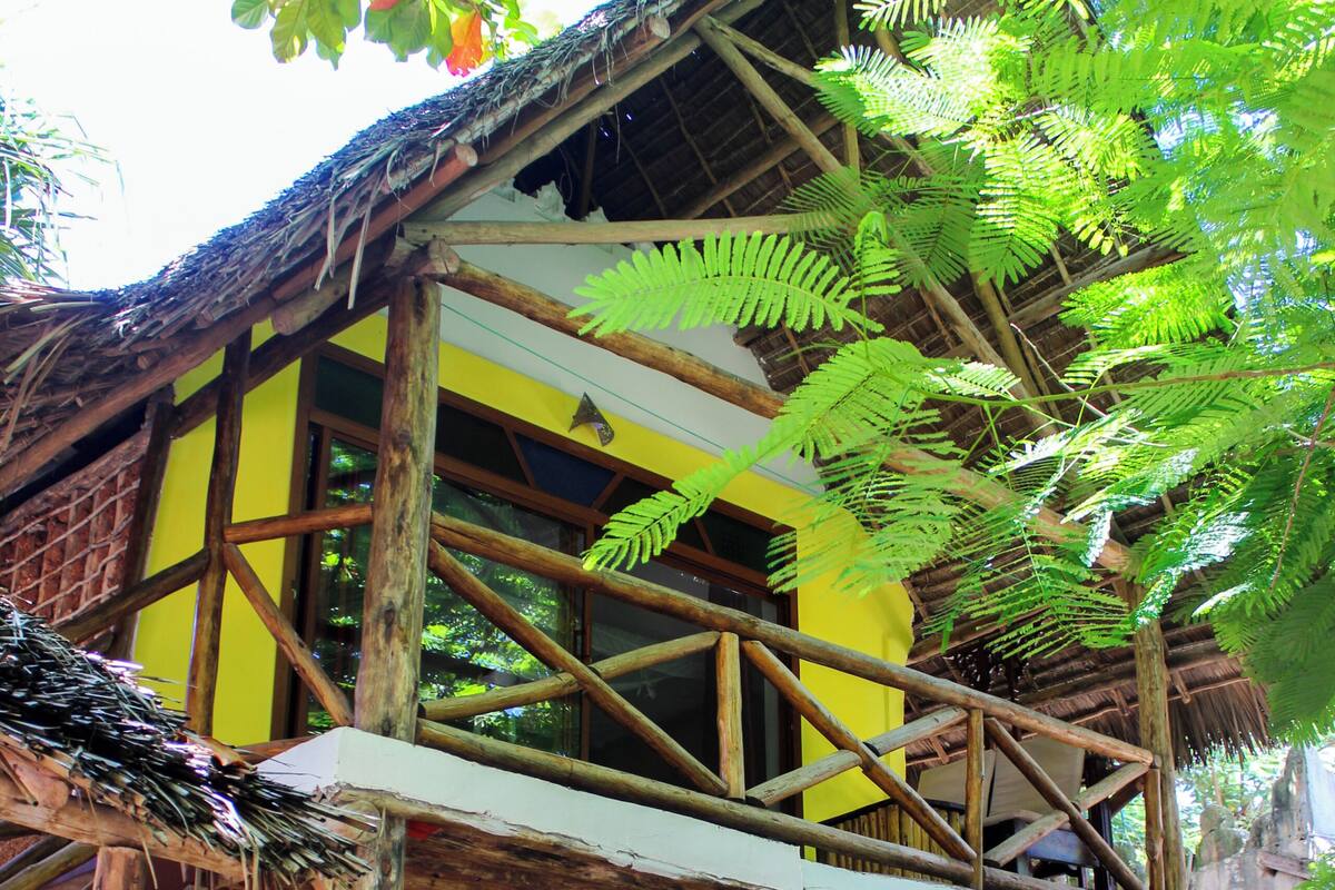 Une structure en bois à plusieurs niveaux, surmontée d’un toit de chaume et entourée d’une végétation luxuriante.