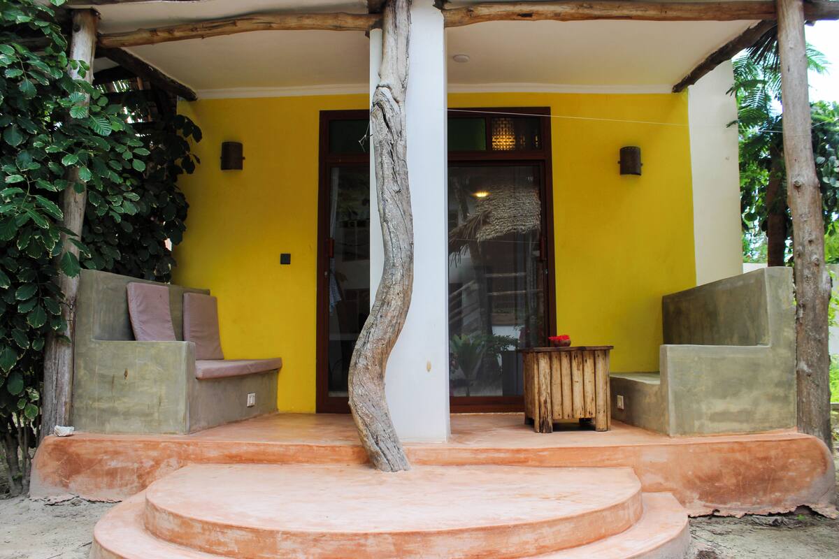 Une entrée d’immeuble avec un banc en béton, une table en bois et une porte en verre.