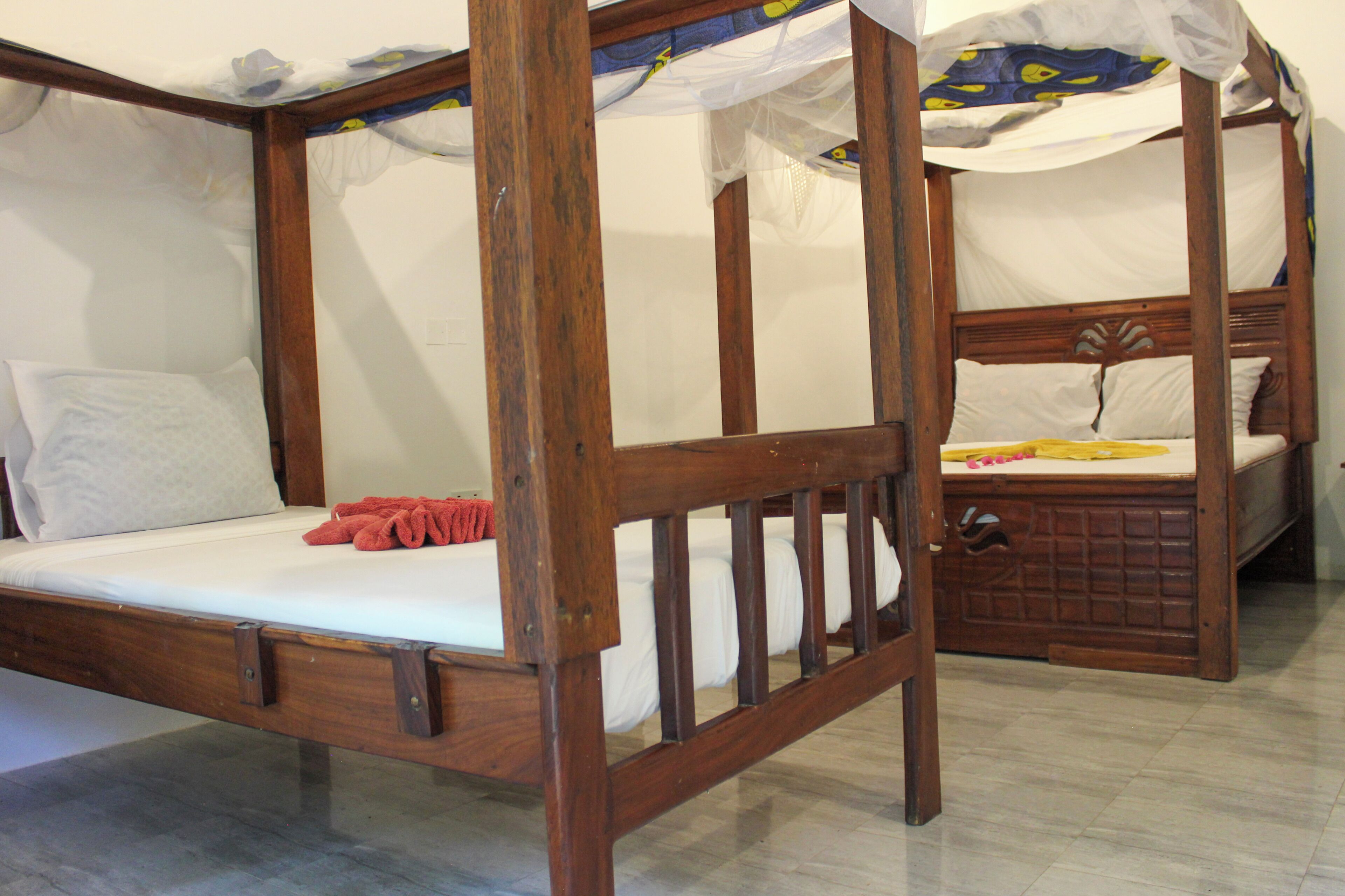 Un lit à baldaquin avec des poteaux aux quatre coins, une structure en bois et du linge de lit blanc.