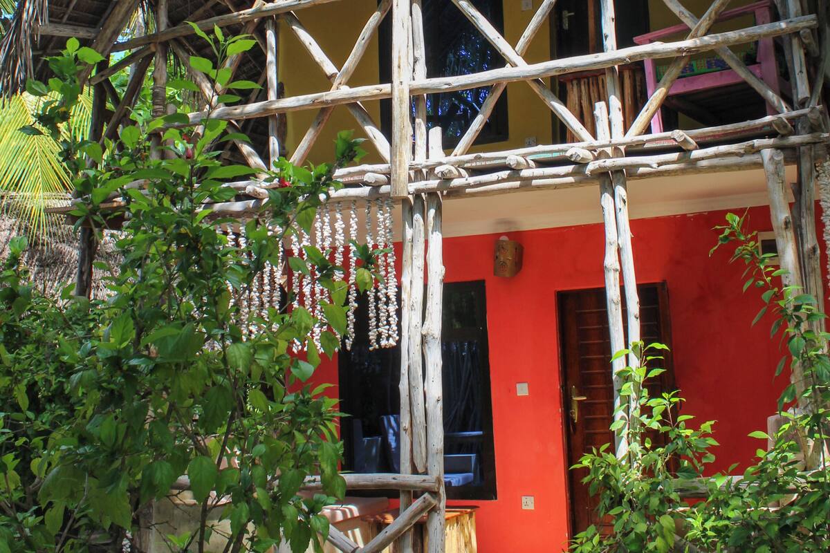Un bâtiment rustique avec un toit de chaume, une échafaudage en bois et un mur rouge.