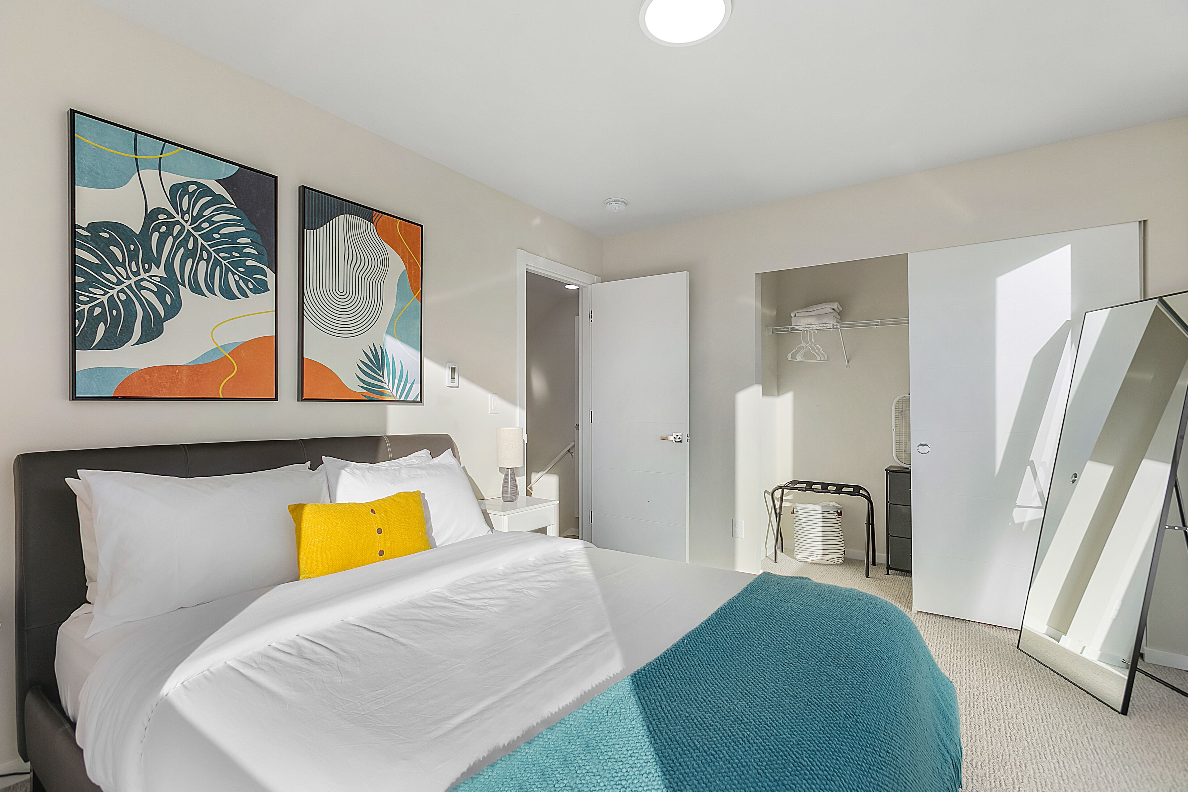 A hotel room with a bed, a large mirror, and artwork on the wall.