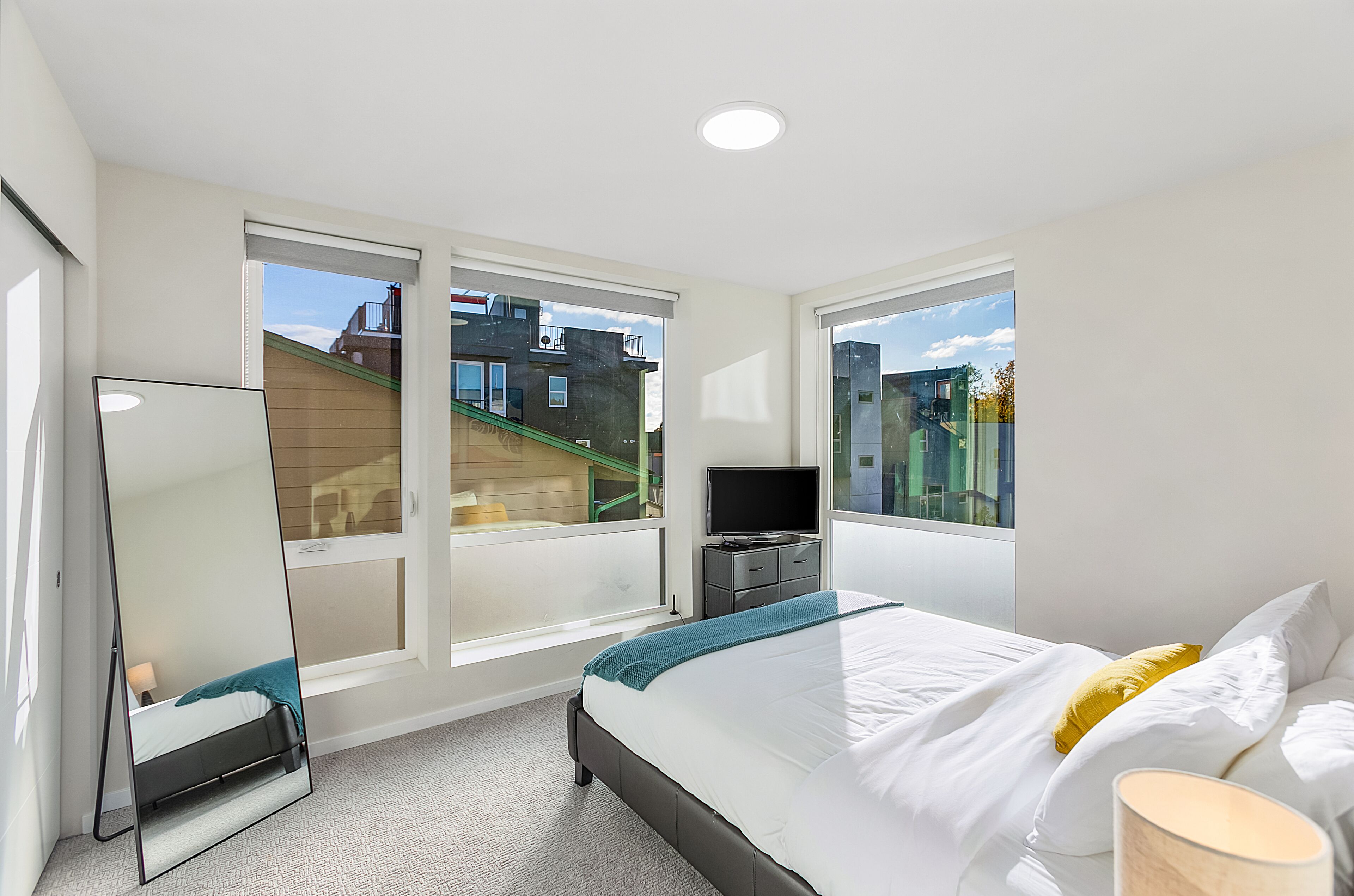 Une chambre d’hôtel moderne dotée d’un grand lit, d’une télévision à écran plat, d’un bureau et d’une fenêtre donnant sur la ville.