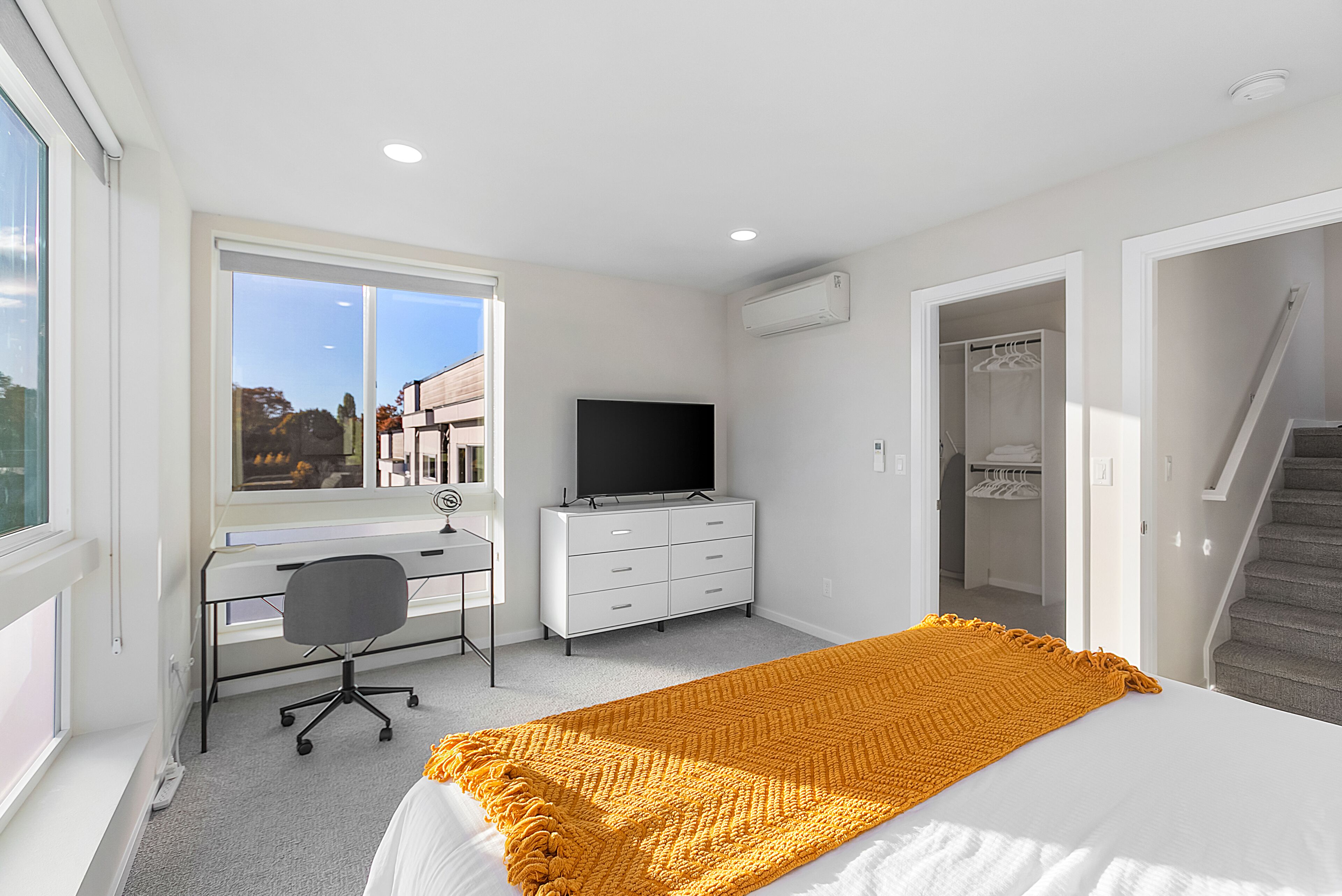 A bedroom with a bed, a desk, a chair, a television, and a closet.
