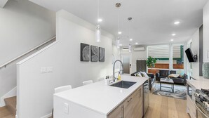 Une cuisine moderne dotée d’un îlot central, un coin repas avec un canapé et une table basse, et un escalier menant à un autre niveau.
