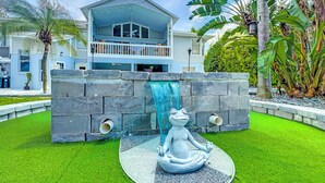 A two-story house with a balcony, a waterfall feature, and a frog statue.