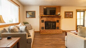 A living room with a brick fireplace, a television mounted above it, and two sofas. - Escape to the Shenandoah River and Relax (Luray)