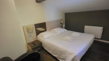 A modern bedroom with a large bed, a massage chair, a bedside table, and a wall-mounted heater.