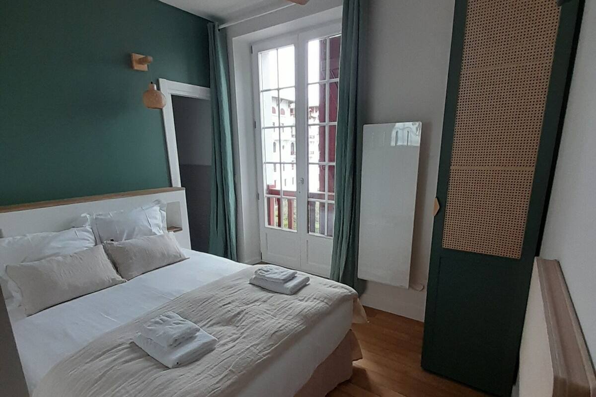 A bedroom with a bed, a window, a ceiling fan, and a door.