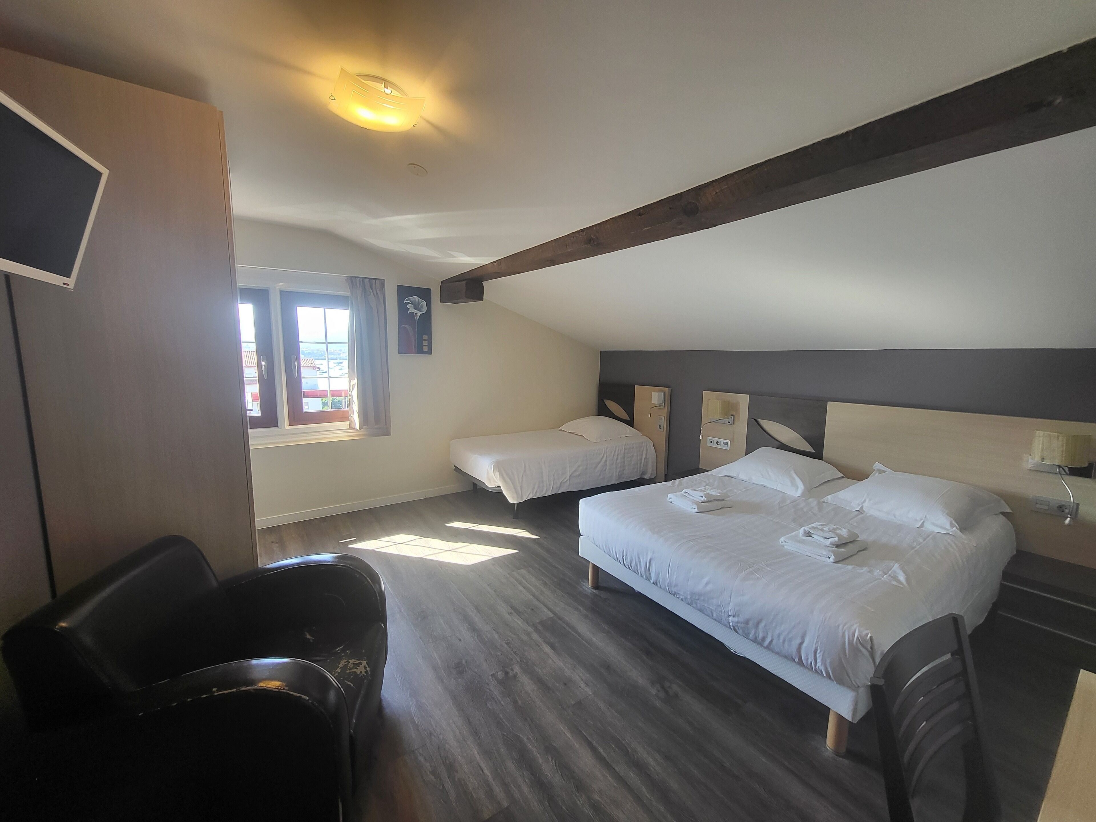 Habitación de hotel con dos camas, un escritorio y una silla.