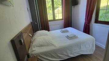 Un dormitorio pequeño y ordenado con una cama individual, un escritorio de madera y una ventana con cortinas.