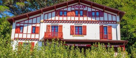 En bygning i to etager med en rød og hvid facade, der er skiltet "HOTEL BELLEVUE".