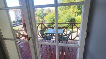 Vista a través de un ventanal hacia una terraza exterior con mesa y sillas.