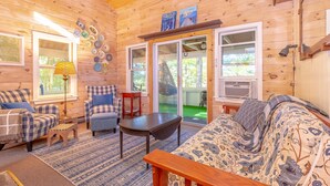 Un interior de cabaña acogedor con muebles escoceses, un sofá estampado y un techo de madera.