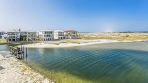 A beachfront property with multiple houses, a dock, and a clear view of the ocean.
