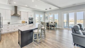 A modern kitchen with a large island, white cabinetry, and a view to the outside.