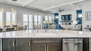 A modern kitchen with a large island, built-in appliances, and a view of the ocean.
