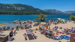 A beach with people, lounge chairs, and a lake.