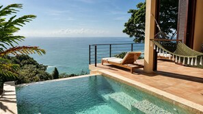 Une piscine avec vue sur l’océan, un hamac et un fauteuil de relaxation.