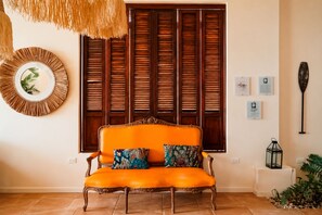 A room with a wooden-framed sofa, a woven wall hanging, and a decorative lantern.