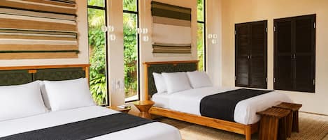 A hotel room with two beds, a large window with a view of greenery, and a wall-mounted air conditioning unit.