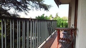 A balcony with a metal railing, a small table, and a chair.