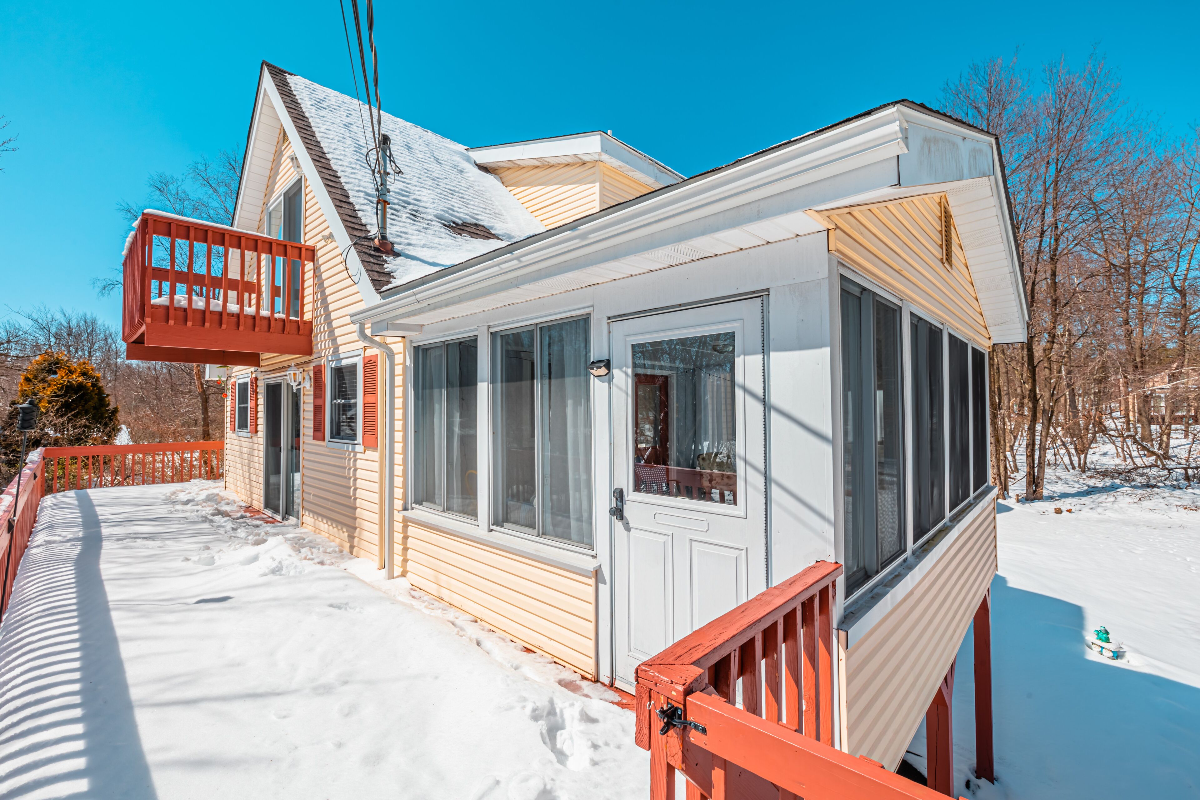 A house with a covered porch, a detached garage, and a snow-covered yard.