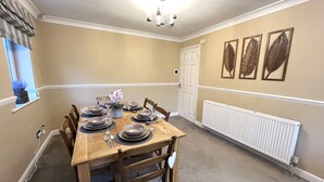 Une salle à manger avec une table en bois, dressée pour quatre personnes, entourée de chaises.