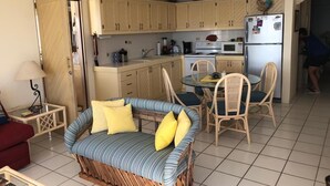 A compact living space with a kitchenette, a dining area with wicker chairs, and a sofa with cushions. - Beach Front Condo with Outstanding Views  (Los Barriles)