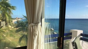 A balcony with a view of the ocean, a chair, and a curtain. - Beach Front Condo with Outstanding Views  (Los Barriles)