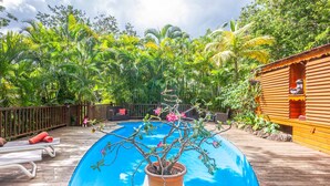 A wooden deck with a pool, surrounded by lush greenery and a wooden cabin. - Cabane Insolite Perchée Dans un Jardin Tropical... Le Nid des Colibris (Deshaies)