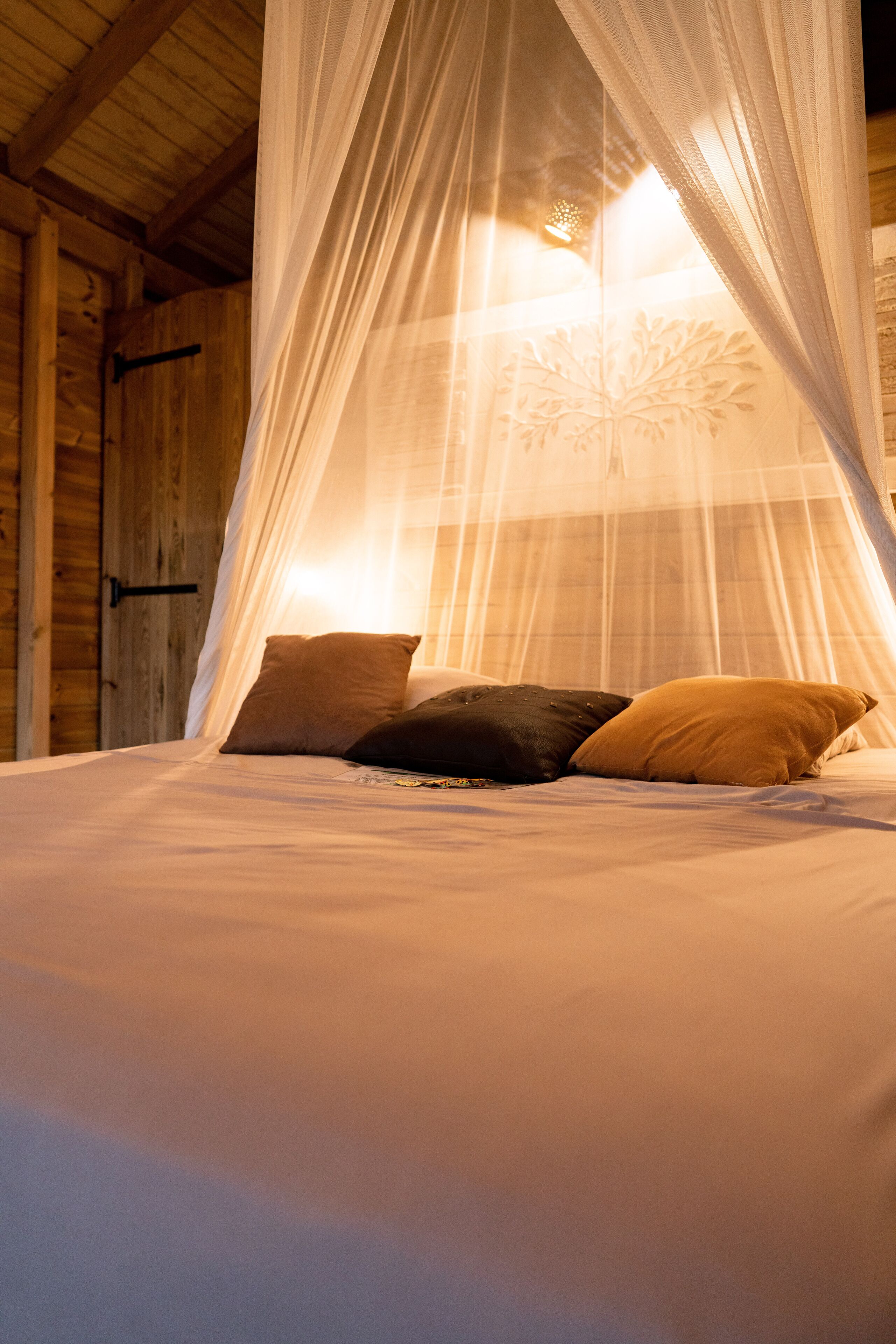 Ein Bett mit Baldachin, Kissen und einer Holzwand.