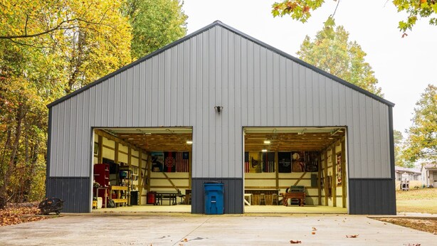 Un grand bâtiment d’un seul étage, doté de deux larges portes de type garage, entouré d’arbres aux feuilles d’automne.