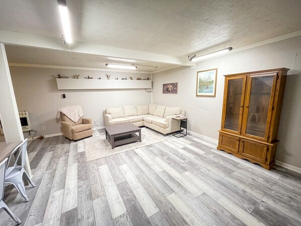 Una sala de estar con un sofá modular, una mesita, un mueble aparador y un transportín para mascotas.