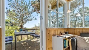 A cozy reading nook with a wooden bookshelf, a comfortable couch, and a table with chairs. - 3 bedroom beautiful home in Grenaa (Grenaa)