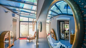Ein modernes Interieur mit Glasdecke, einem Holzschrank und einem Spiegel, der den Raum reflektiert.
