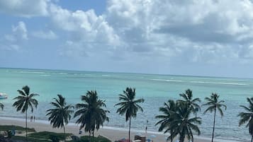 Na praia, areia branca, espreguiçadeiras, guarda-sóis