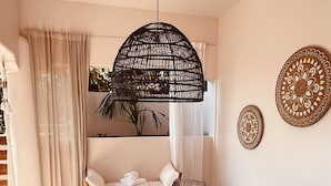 A dining area with a round table, four wicker chairs, a hanging black woven light fixture, and two decorative wall plates. - VERANERA, bas de villa avec vue magnifique sur le pacifique (Puntarenas Province)