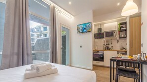 A hotel room with a bed, a desk, and a kitchenette.