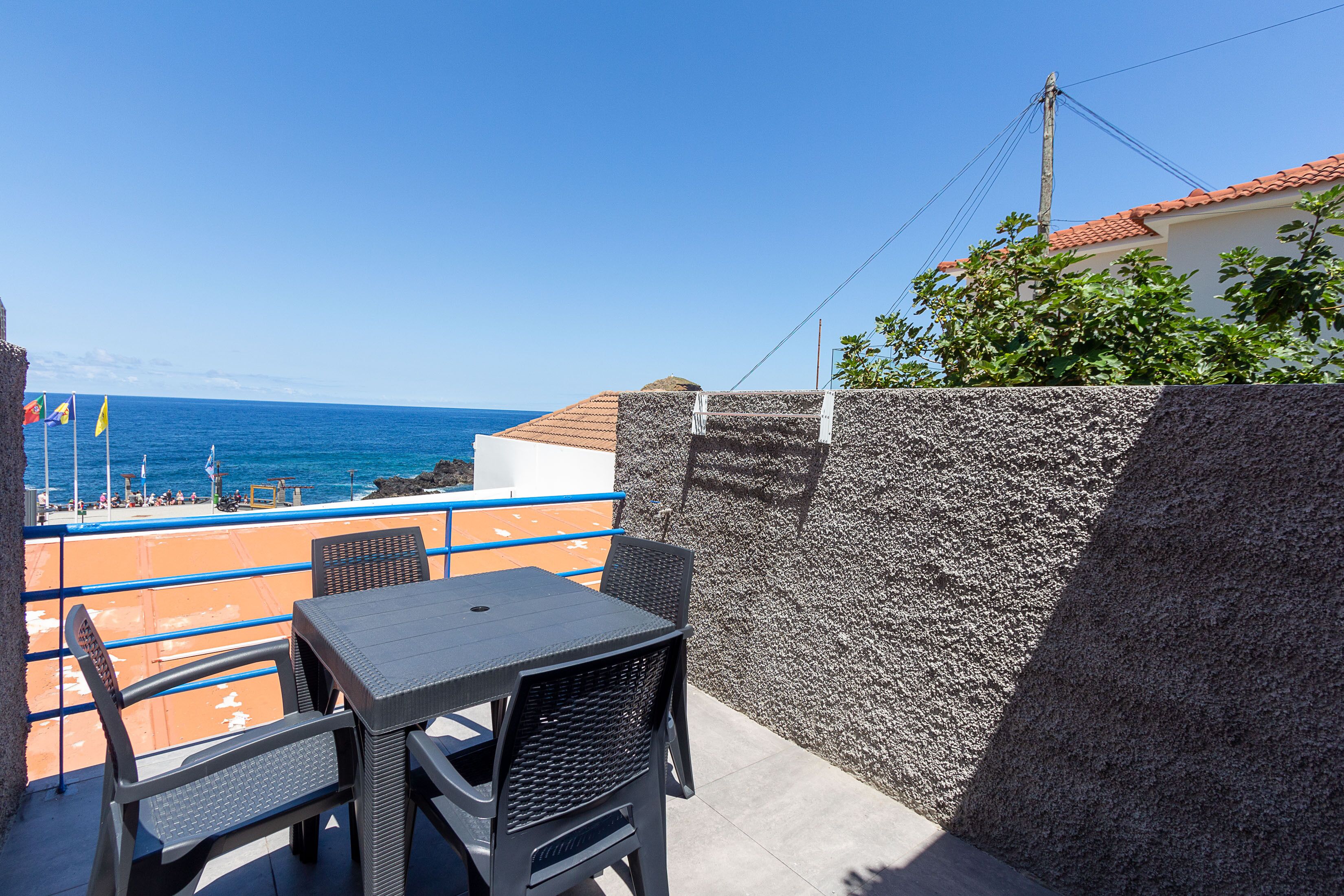 Un balcon avec une table et des chaises donnant sur la mer.