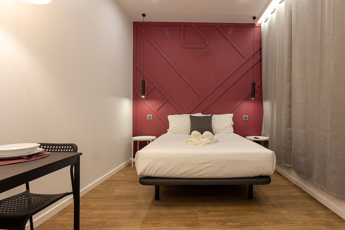 Une chambre d’hôtel moderne équipée d’un lit, de tables de chevet, d’un bureau et d’une chaise.