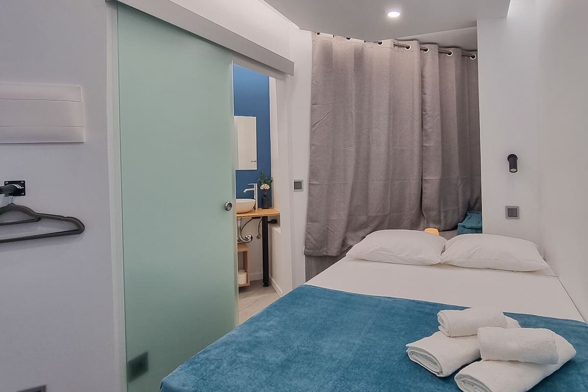 Une chambre d’hôtel moderne équipée d’un lit, d’une salle de bain et d’un espace douche.