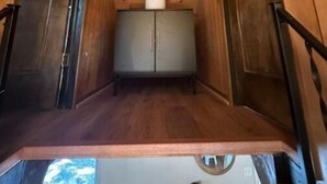 Un couloir étroit en bois, avec une petite armoire et une plante accrochée au mur.
