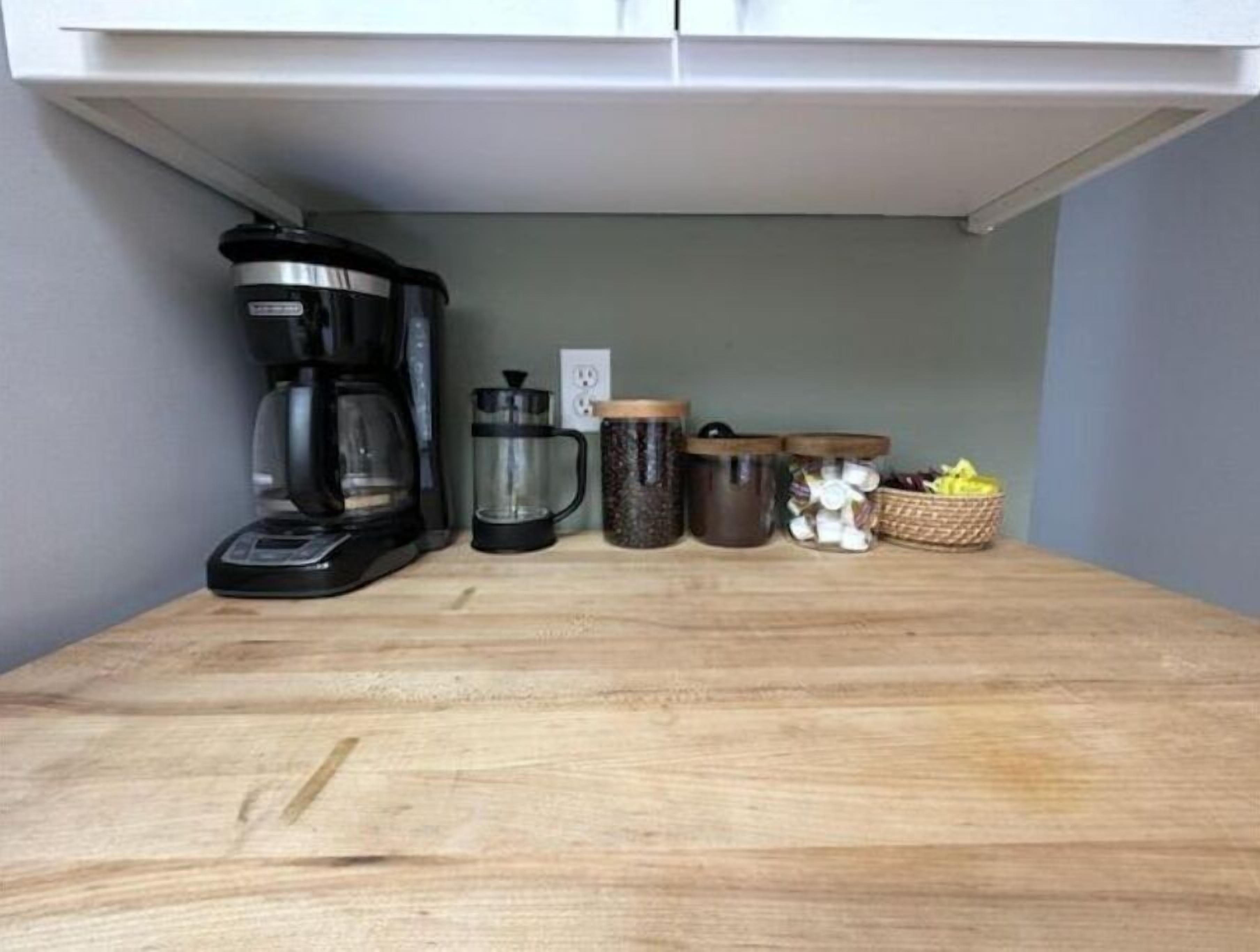 Eine Küchenarbeitsplatte mit Kaffeemaschine, einem French Press und verschiedenen Behältern.